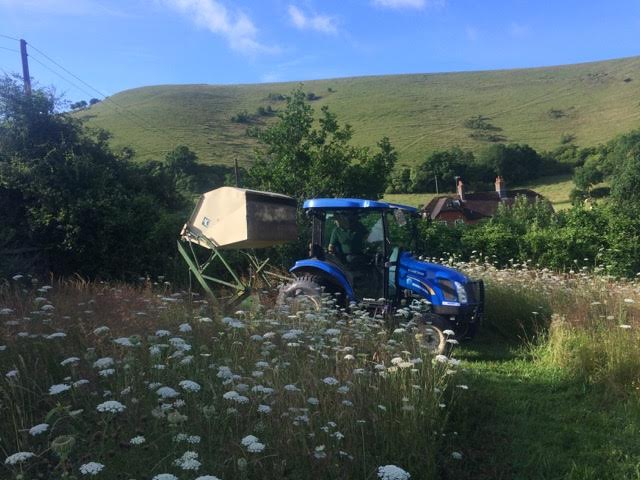 tractor with flail collector in wild flower meadow